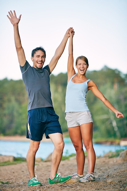 Exitosa pareja de jóvenes atletas levantando los brazos