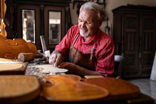 Foto gratuita un experimentado carpintero senior de pelo gris trabajando en su proyecto en el taller de carpintería