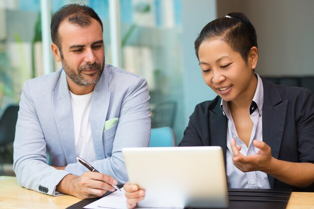 Expertos en marketing latino y asiático positivos sentados juntos