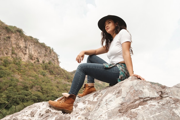 Explorador femenino de ángulo bajo en rocas