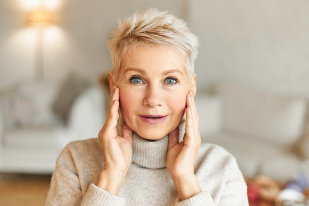 Expresiones faciales humanas positivas, sentimientos, emociones y reacciones. Imagen de mujer madura atractiva emocional con cabello rubio y ojos azules cogidos de la mano en la cara, asombrado con algo