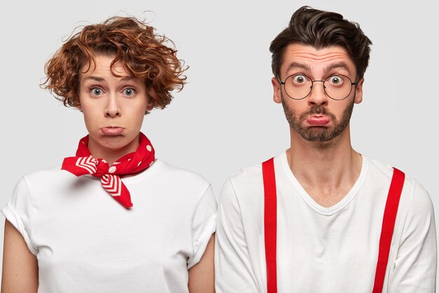 Expresivo hombre y mujer en camisetas blancas posando