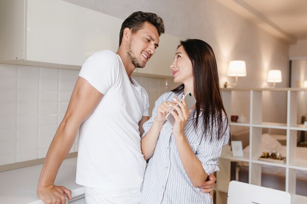 Extasiada mujer morena con cabello largo mirando a los ojos del marido con una sonrisa