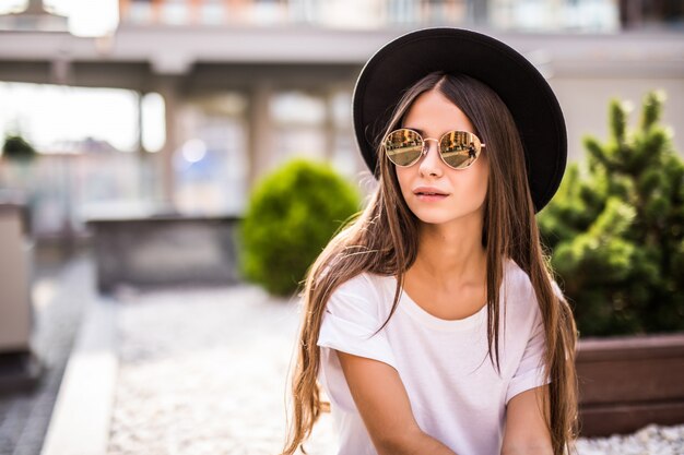 Extática mujer joven con sombrero al aire libre, sentado en el banquillo