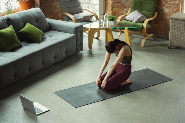 Extensión. Deportiva hermosa joven practicando asanas de yoga como profesional en casa