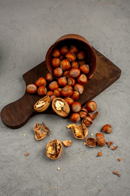 Extienda nueces, nueces y avellanas dentro de una olla marrón sobre un gris