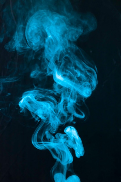 Extracto de los humos de humo azules que se mueven hacia arriba en fondo negro