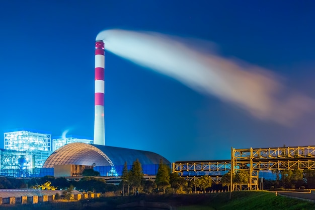 Fábrica con pila de humo contra el cielo por la noche