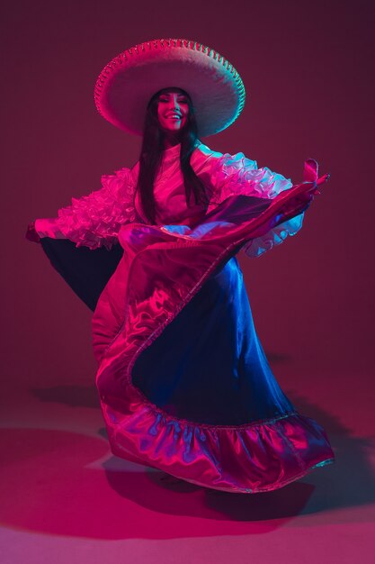 Fabulosa bailarina del Cinco de Mayo en pared púrpura en luz de neón.