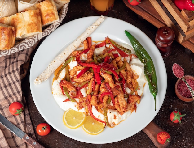 Fajita de pollo, filete de pollo frito con pimiento en lavash con rebanadas de pan en un plato blanco