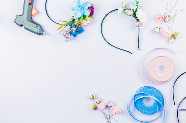 Falsas flores artificiales y cintas para hacer la diadema sobre un fondo blanco.