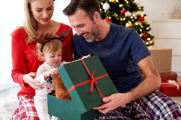 Familia abriendo regalos de Navidad en la cama