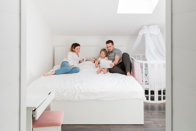 Familia acostada en la cama con tableta