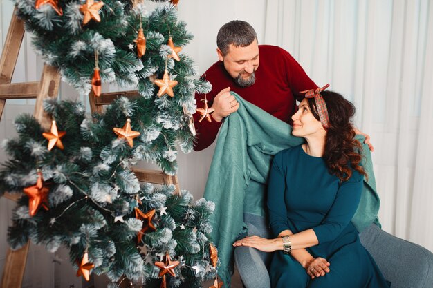 Familia adulta sentada en su casa cerca del árbol de navidad