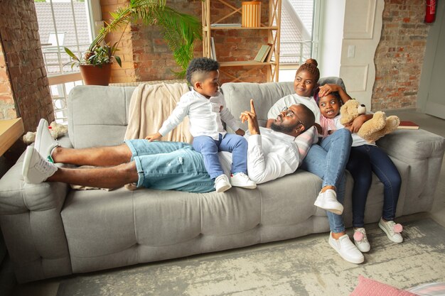 Familia africana joven y alegre pasar tiempo juntos en casa.