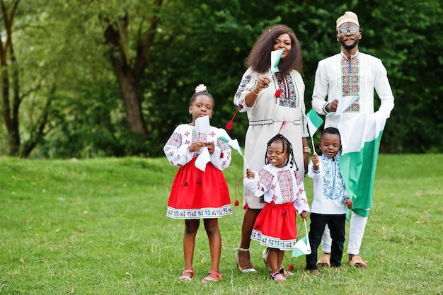 Familia africana en ropa tradicional con banderas nigerianas en el parque