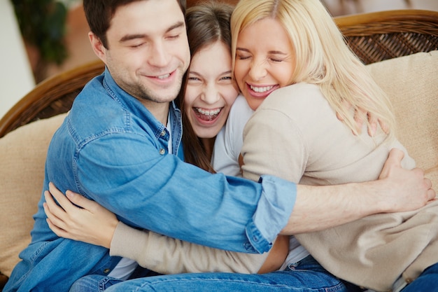 Familia alegre abrazándose en el sofá