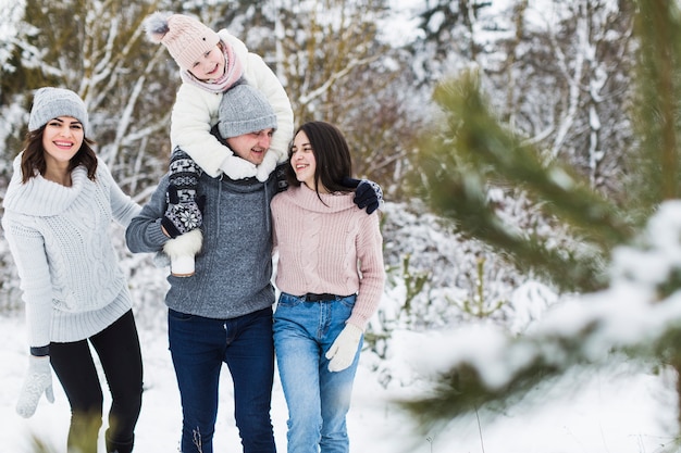 Familia alegre caminando en el bosque de invierno