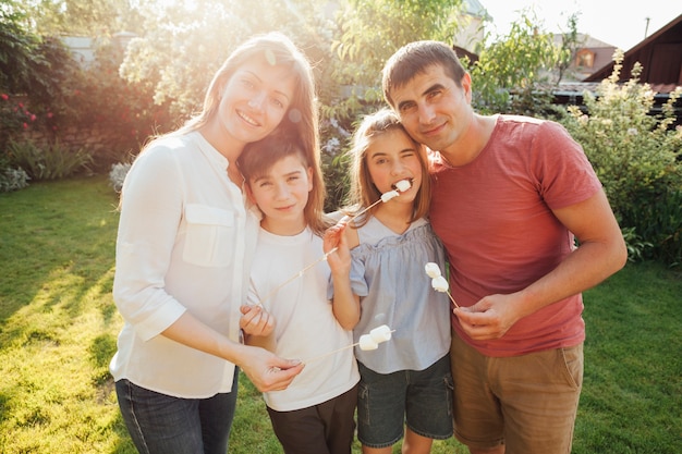 Foto gratuita familia alegre que sostiene el pincho de la melcocha y que mira la cámara