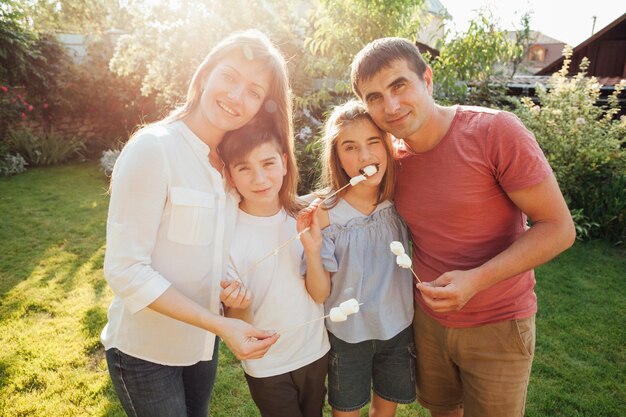 Familia alegre que sostiene el pincho de la melcocha y que mira la cámara