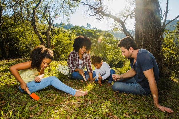 Familia alegre sentada debajo de un árbol