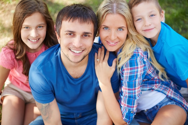 Familia alegre sentados juntos en el parque