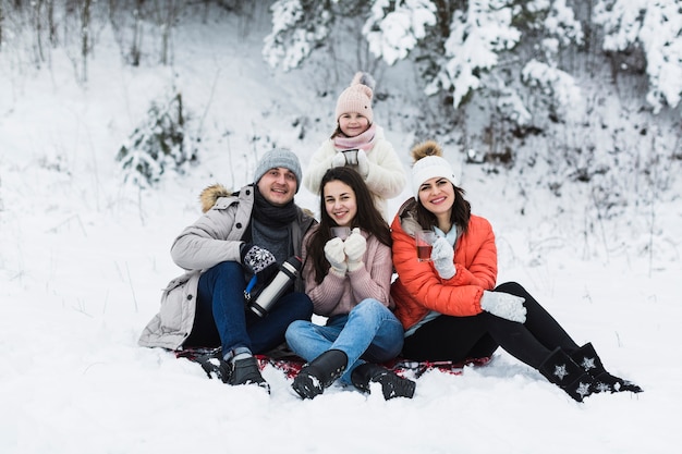 Familia alegre con té en la naturaleza