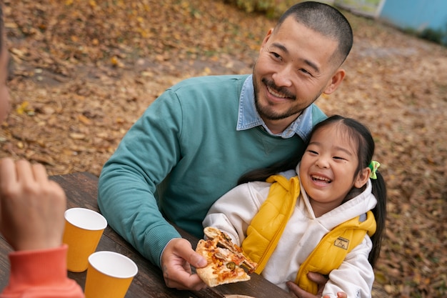 Familia de alto ángulo comiendo pizza al aire libre