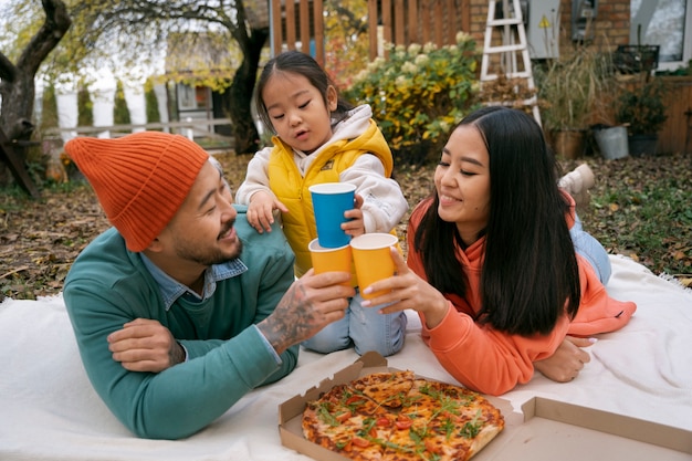 Familia de alto ángulo comiendo pizza al aire libre