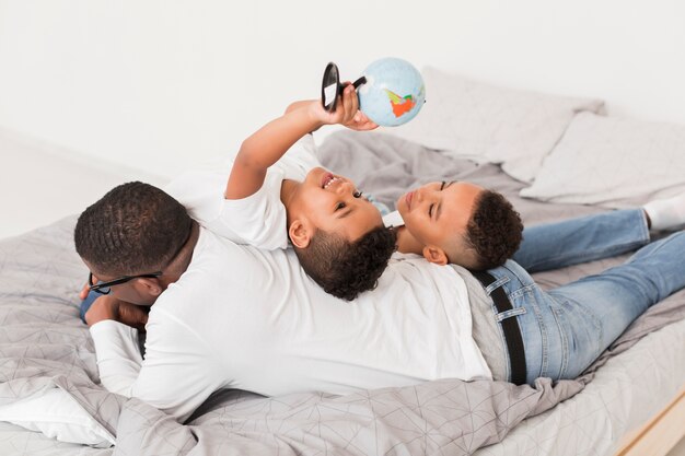 Familia de alto ángulo jugando junto con un pequeño globo en la cama