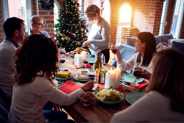 Foto gratuita familia y amigos cenando en casa celebrando la víspera de navidad con comida tradicional y decoración preparando pavo para la cena