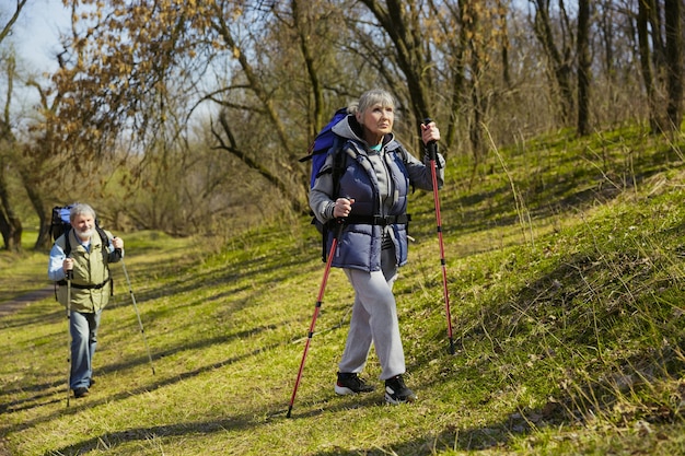 Familia de ancianos pareja de hombre y mujer en traje de turista caminando en el césped verde en un día soleado