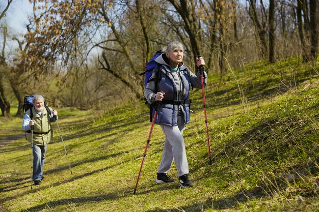 Familia de ancianos pareja de hombre y mujer en traje de turista caminando en el césped verde en un día soleado