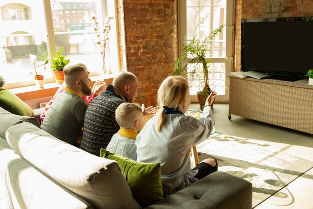 Familia animando y viendo televisión en casa en la sala de estar