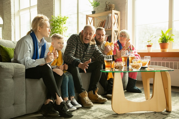 Familia animando y viendo televisión en casa en la sala de estar