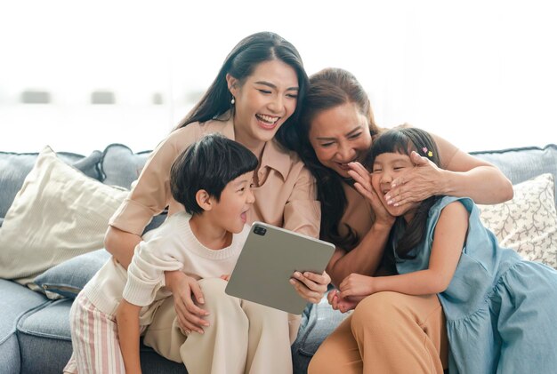 Familia asiática feliz usando tableta digital para vivir en casa relajándose en casa por concepto de estilo de vida