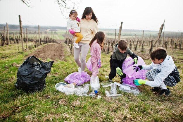 Familia con bolsa de basura recogiendo basura mientras limpia en los viñedos Conservación ambiental y reciclaje ecológico