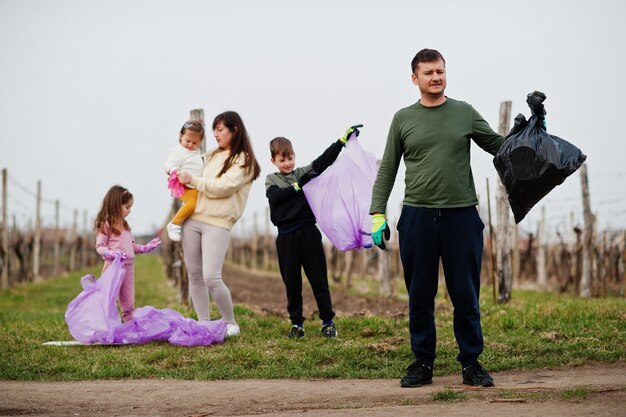 Familia con bolsa de basura recogiendo basura mientras limpia en los viñedos Conservación ambiental y reciclaje ecológico