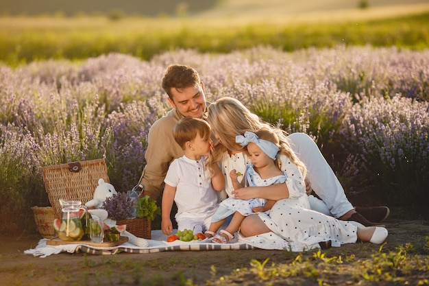 Familia en campo de lavanda. Gente de picnic. Madre con hijos come frutas.