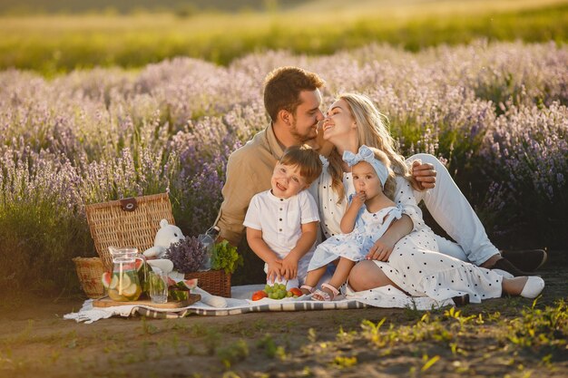 Familia en campo de lavanda. Gente de picnic. Madre con hijos come frutas.