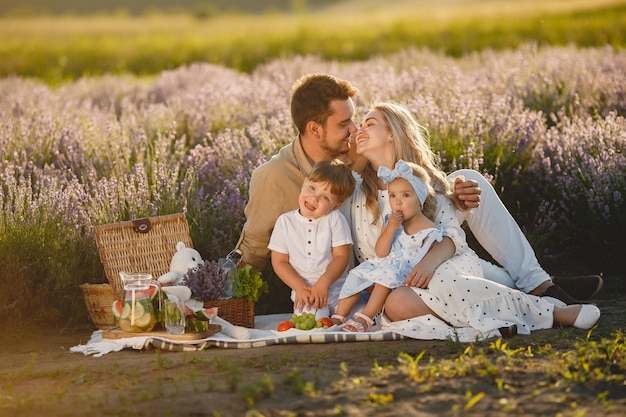 Familia en campo de lavanda. Gente de picnic. Madre con hijos come frutas.