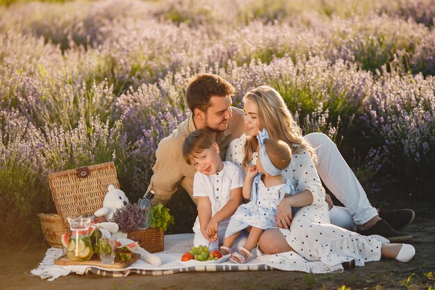 Familia en campo de lavanda. Gente de picnic. Madre con hijos come frutas.