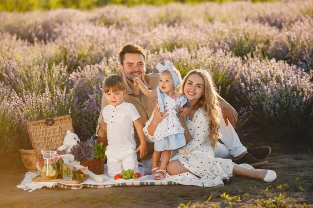 Familia en campo de lavanda. Gente de picnic. Madre con hijos come frutas.