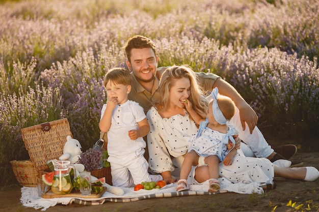 Familia en campo de lavanda. Gente de picnic. Madre con hijos come frutas.