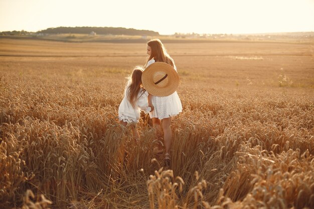 Familia en un campo de trigo. Mujer con un vestido blanco. Chica con sombrero de paja.