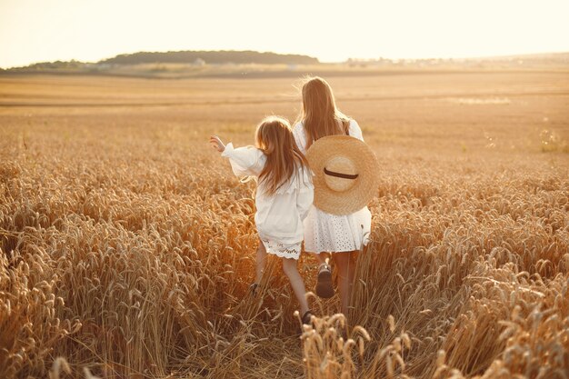 Familia en un campo de trigo. Mujer con un vestido blanco. Chica con sombrero de paja.