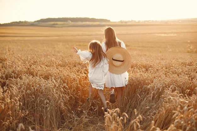 Familia en un campo de trigo. Mujer con un vestido blanco. Chica con sombrero de paja.