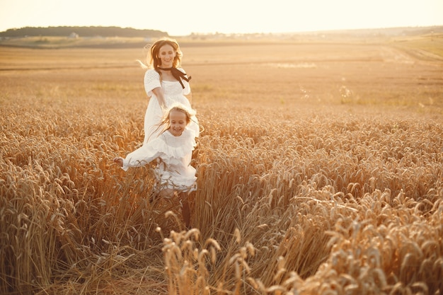 Familia en un campo de trigo. Mujer con un vestido blanco. Chica con sombrero de paja.