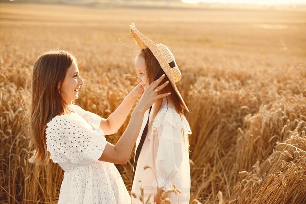 Familia en un campo de trigo. Mujer con un vestido blanco. Chica con sombrero de paja.