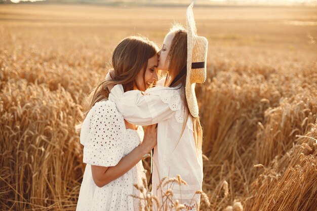 Familia en un campo de trigo. Mujer con un vestido blanco. Chica con sombrero de paja.